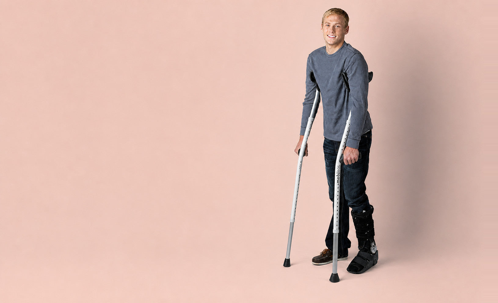 Alex standing with Mobilegs Ultra crutches on a peach studio background